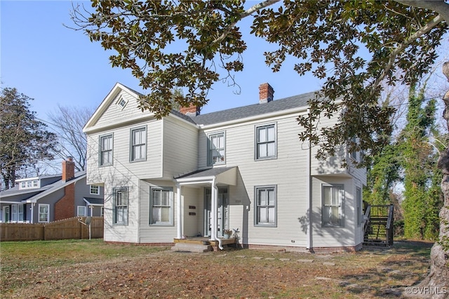 view of front of house with a front yard, a chimney, and fence