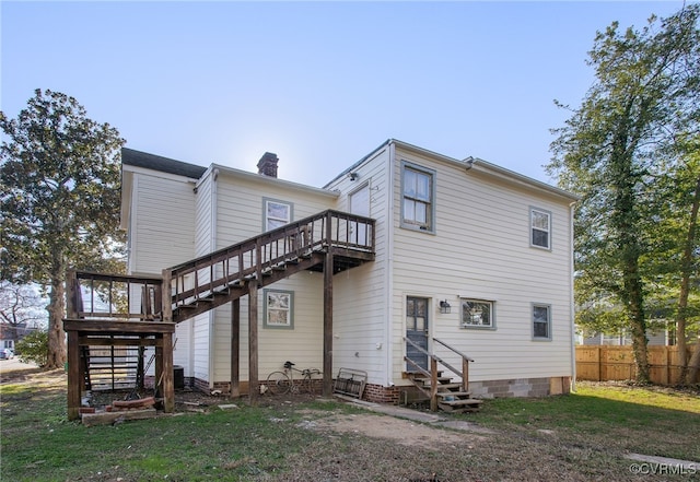 rear view of house featuring fence, a chimney, stairs, entry steps, and a lawn