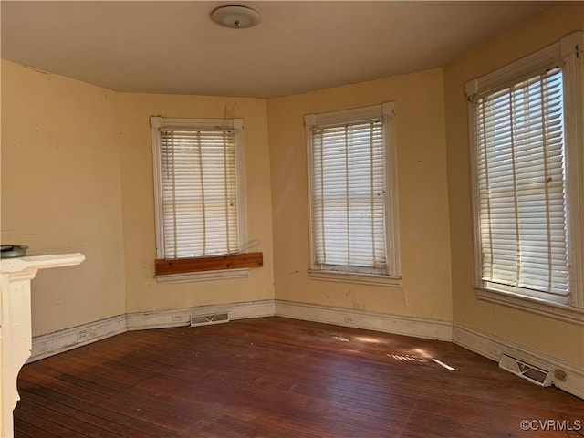 empty room featuring visible vents, baseboards, and wood-type flooring