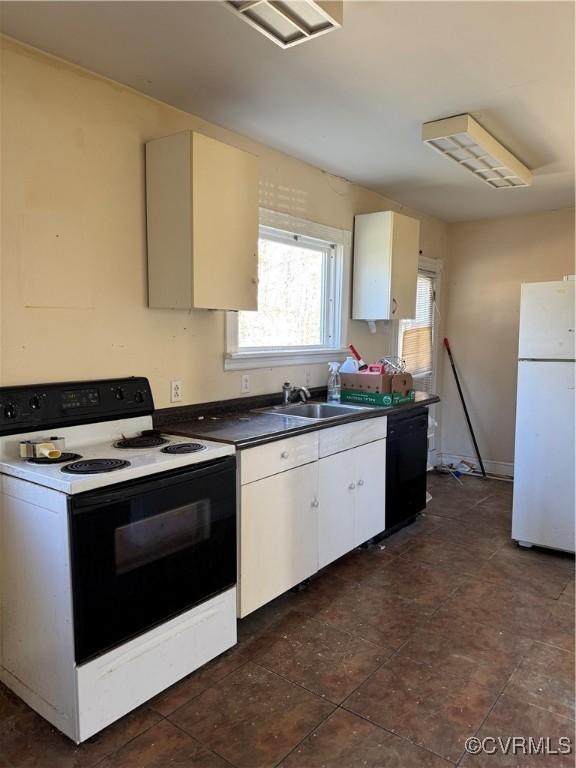 kitchen featuring a sink, black dishwasher, dark countertops, electric range oven, and freestanding refrigerator