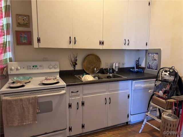 kitchen with white appliances, dark wood-style flooring, a sink, white cabinetry, and dark countertops