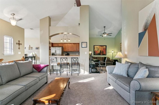 living room featuring ceiling fan, high vaulted ceiling, and light carpet