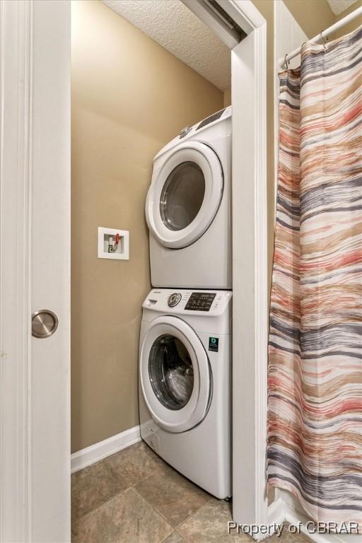 washroom with stacked washer / drying machine and a textured ceiling