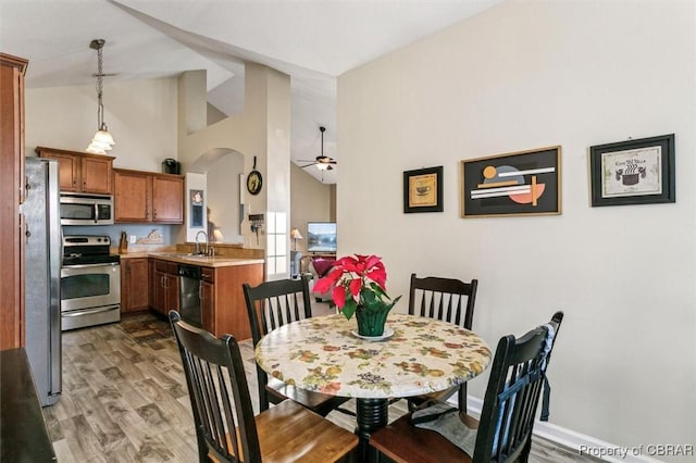 dining room featuring dark wood-type flooring, ceiling fan, high vaulted ceiling, and sink