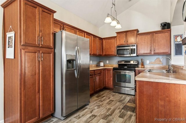 kitchen with sink, wood-type flooring, high vaulted ceiling, appliances with stainless steel finishes, and pendant lighting