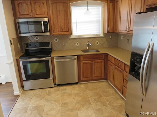 kitchen featuring appliances with stainless steel finishes, decorative light fixtures, sink, and backsplash