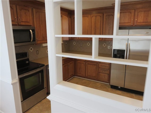 kitchen with light tile patterned flooring, appliances with stainless steel finishes, and backsplash