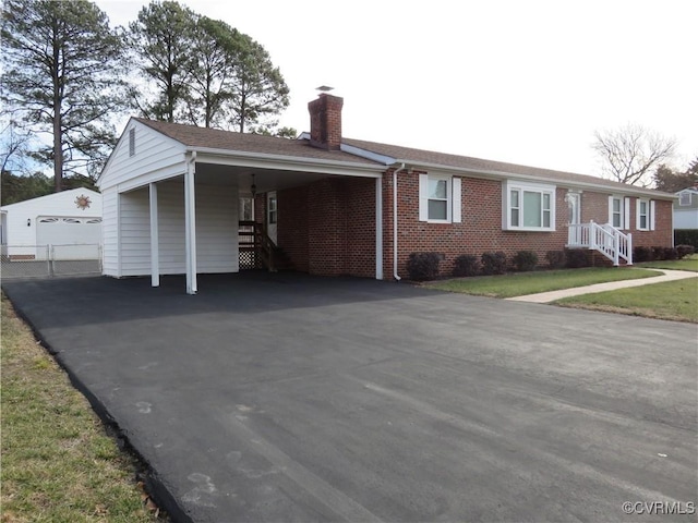 ranch-style house featuring a carport, a garage, an outdoor structure, and a front yard