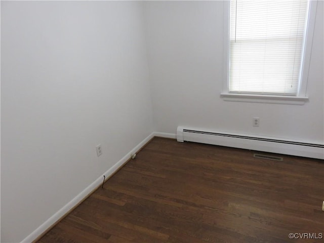 unfurnished room featuring a baseboard heating unit and dark wood-type flooring