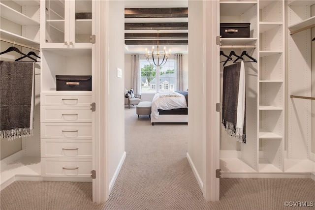 spacious closet with light colored carpet, a notable chandelier, and beam ceiling