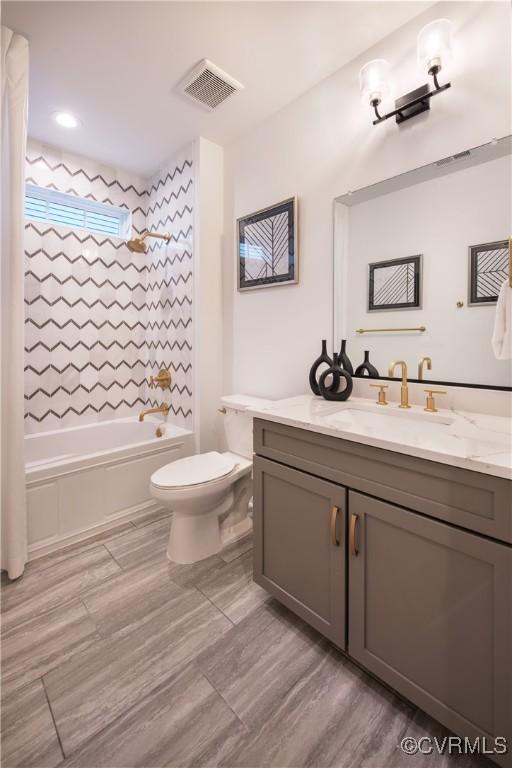 full bathroom featuring tiled shower / bath, vanity, and toilet