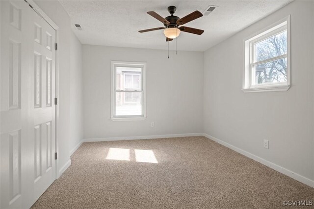 carpeted spare room with ceiling fan and a textured ceiling