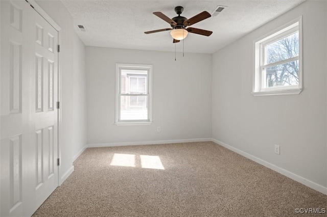 empty room featuring visible vents, baseboards, carpet floors, and a textured ceiling