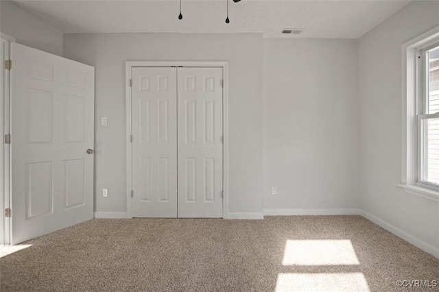 unfurnished bedroom with a closet, carpet floors, baseboards, and visible vents