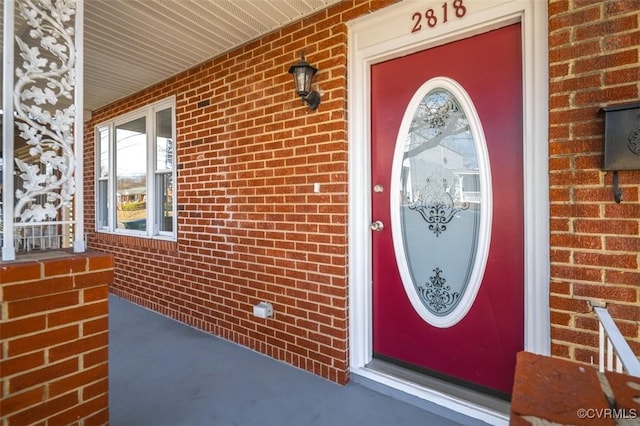 entrance to property with brick siding and a porch