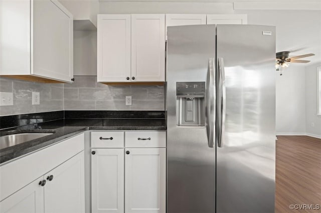 kitchen with dark stone countertops, backsplash, wood-type flooring, white cabinets, and stainless steel fridge with ice dispenser