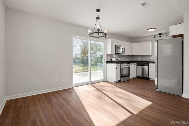 kitchen featuring appliances with stainless steel finishes, dark hardwood / wood-style floors, pendant lighting, white cabinets, and backsplash