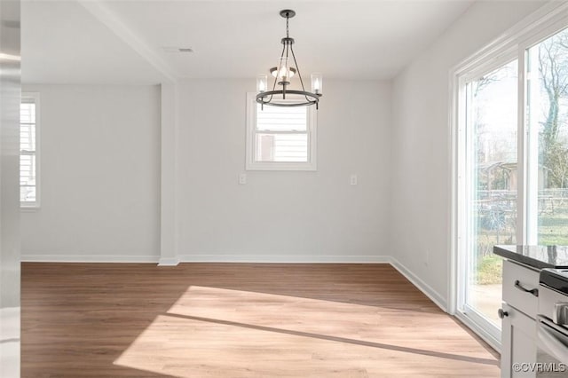 unfurnished room featuring a notable chandelier, baseboards, and light wood finished floors