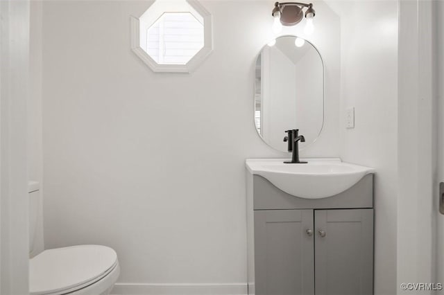 bathroom featuring vanity, toilet, and baseboards