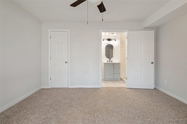 unfurnished bedroom with ceiling fan, ensuite bath, and light carpet