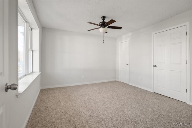 carpeted spare room featuring ceiling fan and a textured ceiling