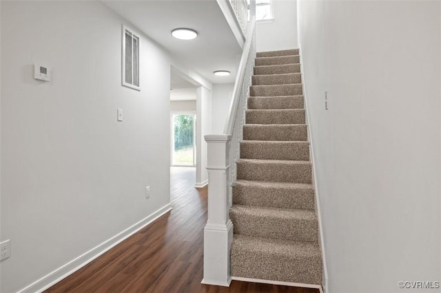 stairway with wood finished floors, visible vents, and baseboards