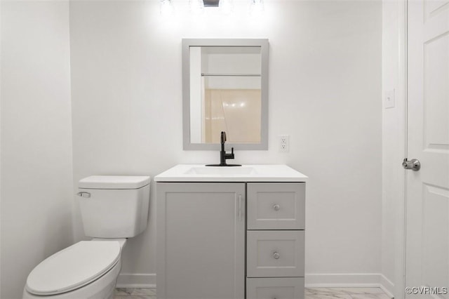 bathroom with vanity, toilet, baseboards, and marble finish floor