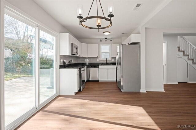 kitchen featuring sink, an inviting chandelier, hanging light fixtures, stainless steel appliances, and white cabinets