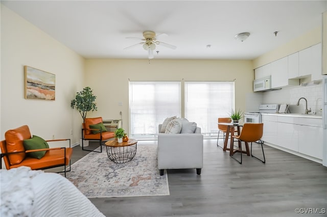 living room featuring sink, dark wood-type flooring, and ceiling fan