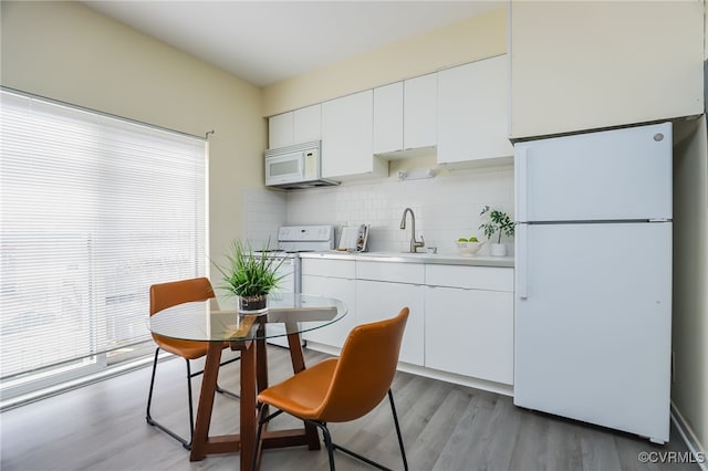 kitchen with white appliances, sink, decorative backsplash, and white cabinets