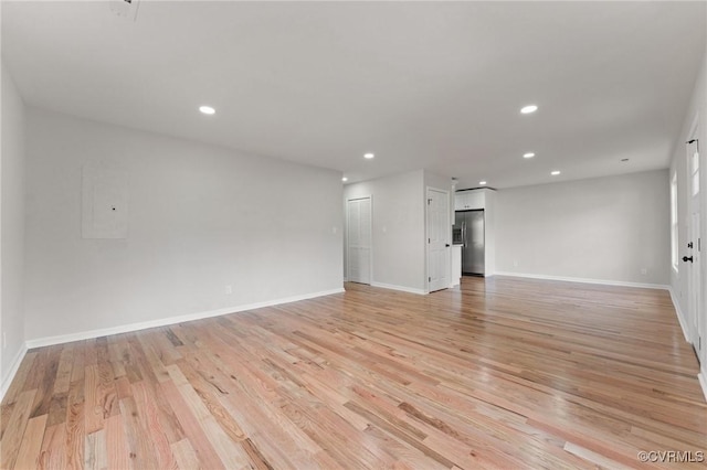 unfurnished room featuring electric panel and light hardwood / wood-style flooring