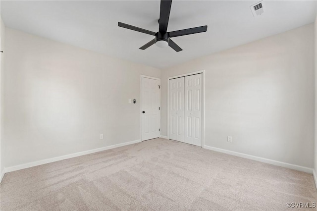 unfurnished bedroom featuring ceiling fan, a closet, and light carpet