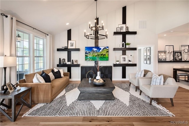 living room featuring an inviting chandelier, high vaulted ceiling, and light hardwood / wood-style floors