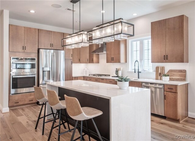 kitchen featuring pendant lighting, sink, appliances with stainless steel finishes, a center island, and light hardwood / wood-style floors