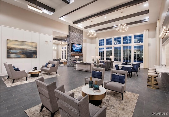 interior space with a stone fireplace, beamed ceiling, a chandelier, and a towering ceiling