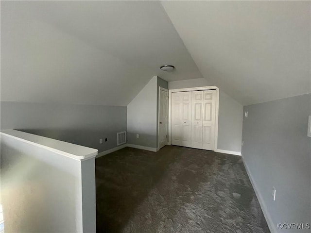 additional living space with dark carpet and vaulted ceiling