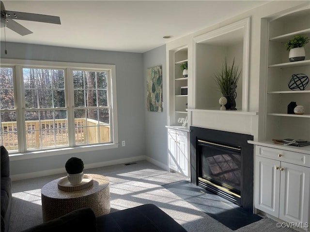 living room with built in shelves and ceiling fan