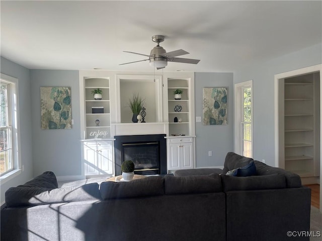 living room with built in shelves and ceiling fan