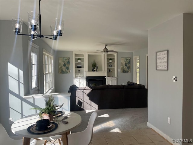 tiled dining room featuring ceiling fan with notable chandelier and built in features