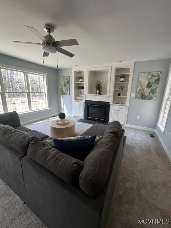 living room with carpet floors, a healthy amount of sunlight, built in features, and ceiling fan