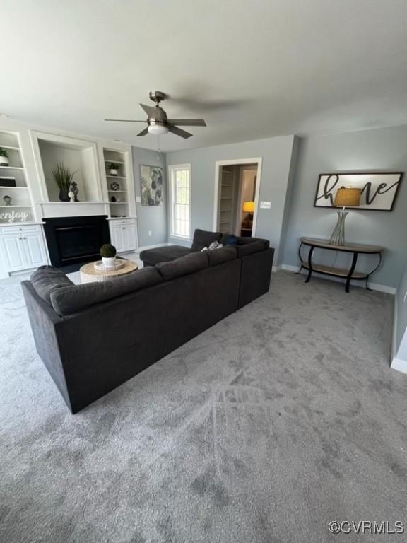 carpeted living room with built in features and ceiling fan