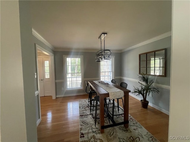 dining space with ornamental molding, an inviting chandelier, and light hardwood / wood-style floors