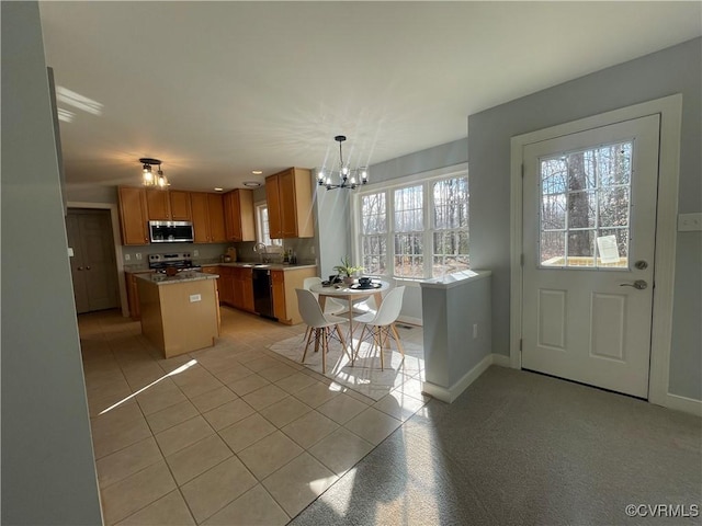 kitchen featuring an inviting chandelier, light tile patterned floors, appliances with stainless steel finishes, a kitchen island, and pendant lighting