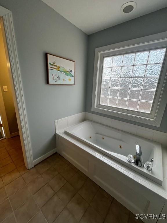 bathroom with a relaxing tiled tub and tile patterned floors