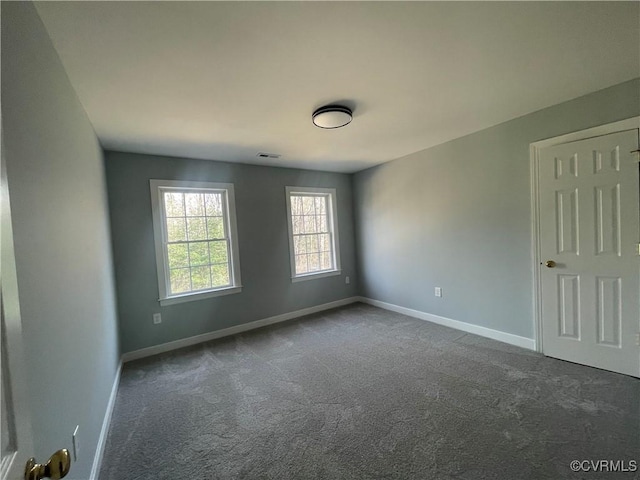 spare room featuring dark carpet