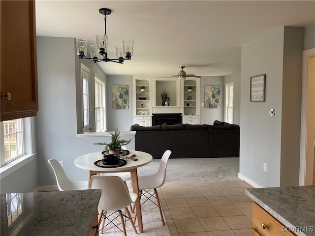 tiled dining area with a healthy amount of sunlight and ceiling fan with notable chandelier