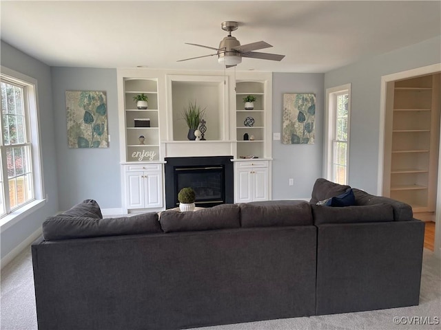 living room with built in features and ceiling fan