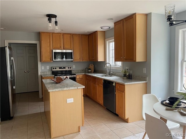 kitchen featuring stainless steel appliances, hanging light fixtures, sink, and a kitchen island