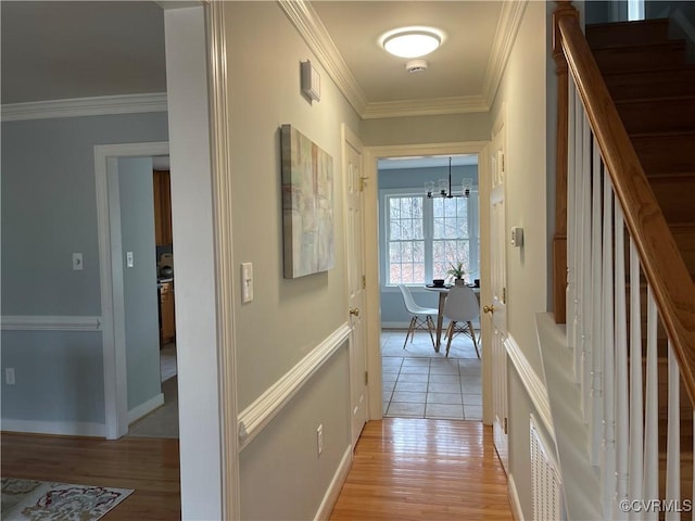 hall with crown molding, an inviting chandelier, and light hardwood / wood-style flooring