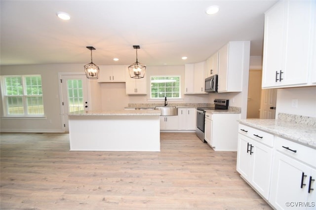 kitchen featuring light stone counters, stainless steel appliances, a kitchen island, and white cabinets